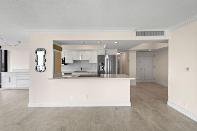 kitchen featuring a textured ceiling, stainless steel appliances, white cabinetry, and crown molding