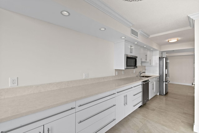 kitchen with sink, ornamental molding, light tile patterned flooring, white cabinetry, and stainless steel appliances