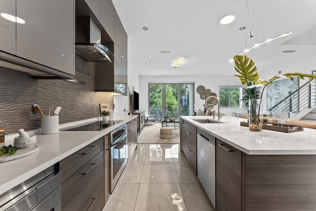 kitchen with a spacious island, wall chimney range hood, stainless steel appliances, backsplash, and sink