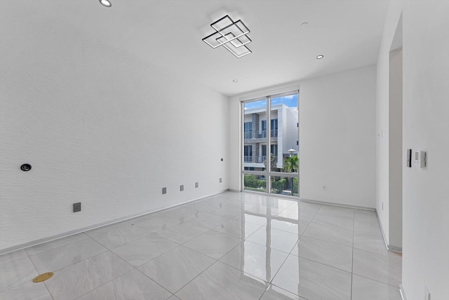 unfurnished room featuring a wall of windows and light tile patterned floors