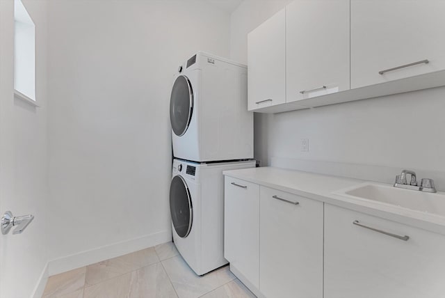 washroom with cabinets, light tile patterned flooring, stacked washer and clothes dryer, and sink