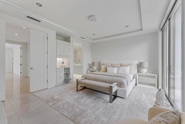 bedroom with ensuite bath and a raised ceiling