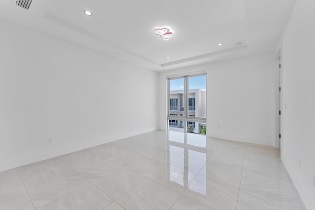 tiled empty room with a raised ceiling