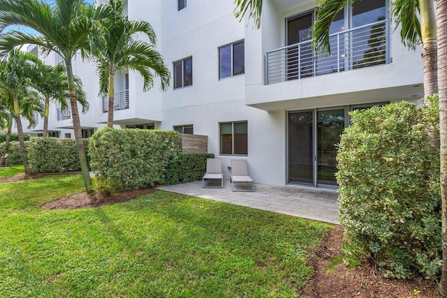 exterior space with a patio area, a lawn, and a balcony