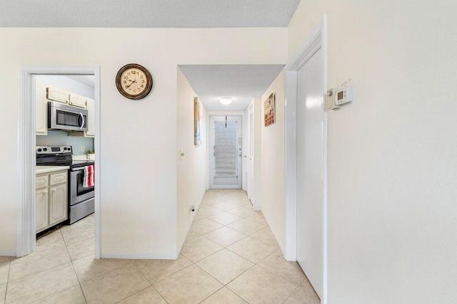 corridor with light tile patterned floors and a textured ceiling