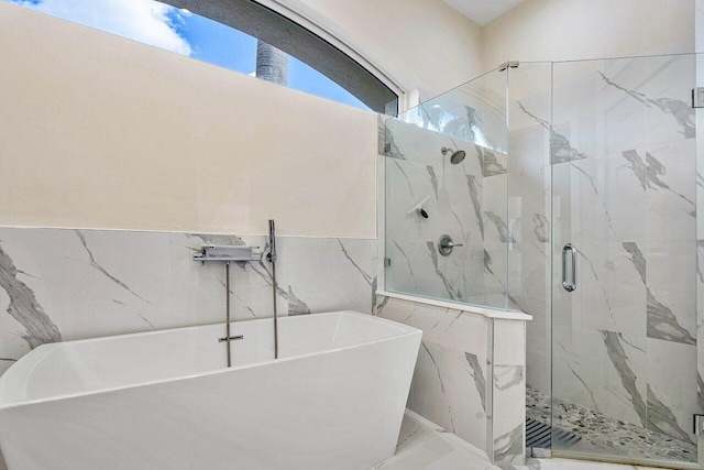 bathroom with shower with separate bathtub and tile walls