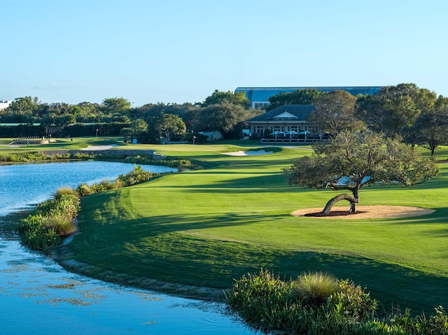 surrounding community with a water view and a lawn