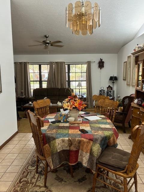 dining space featuring a textured ceiling, ceiling fan with notable chandelier, a healthy amount of sunlight, and light tile patterned floors