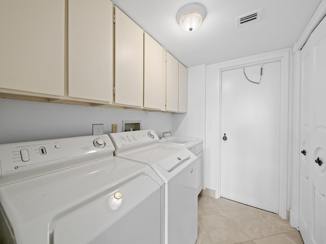 clothes washing area with cabinets, sink, washing machine and clothes dryer, and light tile patterned flooring