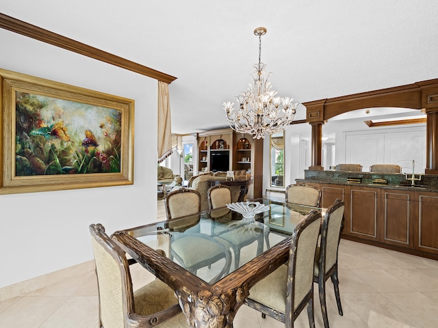 dining room with sink, ornate columns, light tile patterned flooring, a chandelier, and ornamental molding