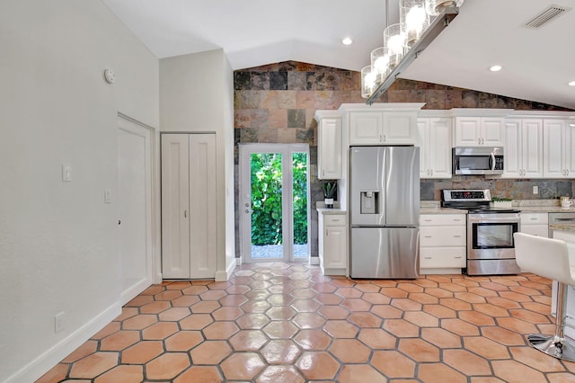 kitchen with white cabinets, light tile patterned floors, stainless steel appliances, and lofted ceiling