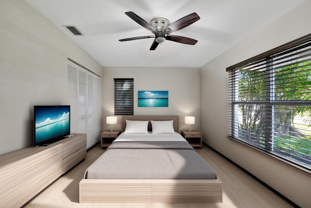 bedroom featuring a closet, multiple windows, light hardwood / wood-style floors, and ceiling fan