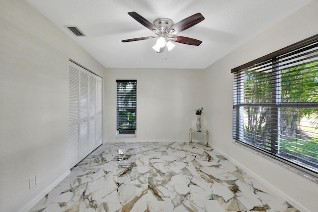 unfurnished bedroom with ceiling fan, a textured ceiling, and a closet