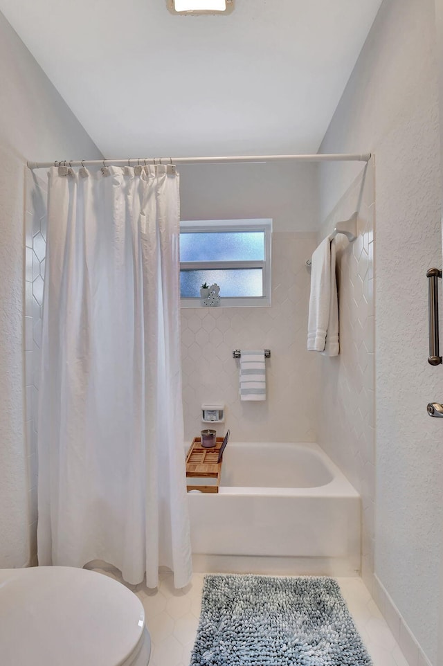 bathroom featuring tile patterned floors, toilet, and shower / bathtub combination with curtain