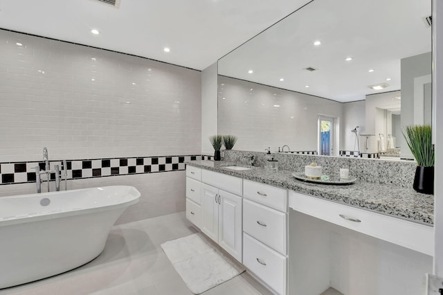 bathroom with tile patterned floors, a washtub, vanity, and tile walls