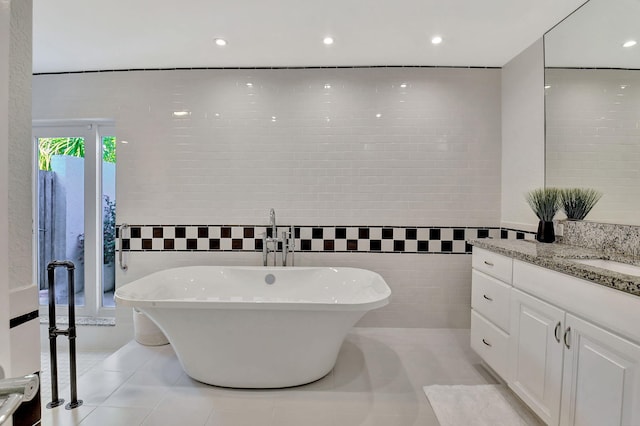 bathroom featuring vanity, tile patterned floors, tile walls, and a bathing tub