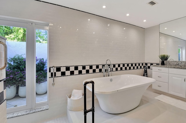 bathroom featuring tile patterned floors, vanity, a tub, and tile walls