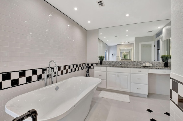 bathroom with tile patterned flooring, vanity, a bath, and tile walls