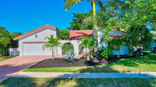 mediterranean / spanish home featuring a garage and a front lawn