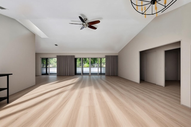 unfurnished living room featuring ceiling fan with notable chandelier, a healthy amount of sunlight, and lofted ceiling