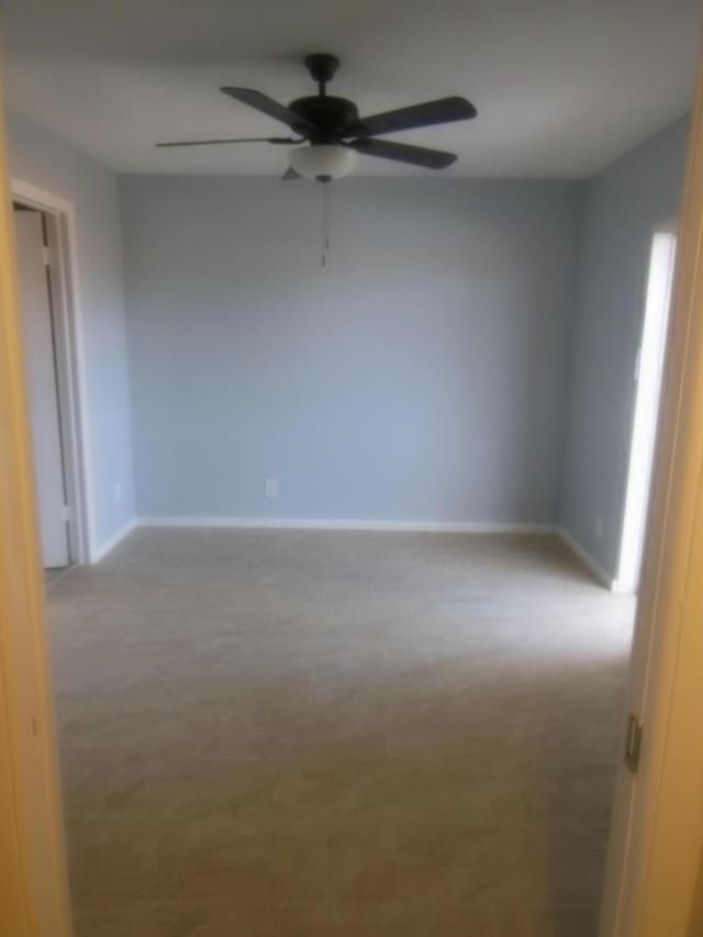 carpeted spare room with ceiling fan