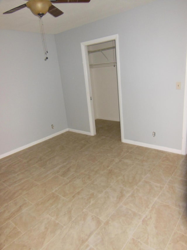 unfurnished bedroom with a closet, a walk in closet, light tile patterned floors, and ceiling fan