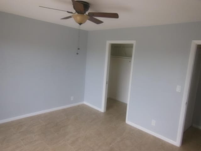 unfurnished bedroom with ceiling fan, a closet, and a walk in closet