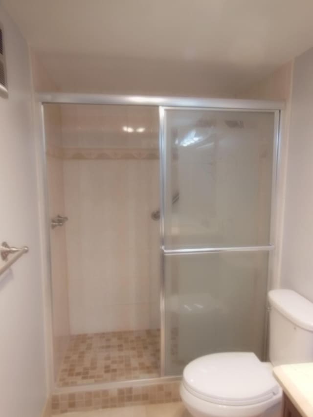 bathroom featuring vanity, toilet, a shower with door, and tile patterned floors