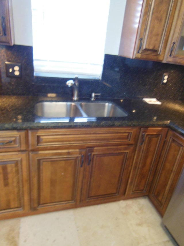 kitchen featuring tasteful backsplash, dark stone counters, and sink