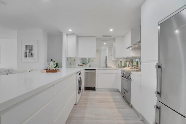 kitchen featuring washer / dryer, light hardwood / wood-style flooring, stainless steel appliances, sink, and white cabinetry