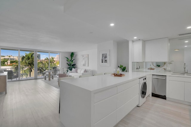 kitchen featuring washer / dryer, kitchen peninsula, white cabinetry, light wood-type flooring, and dishwasher