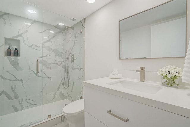 bathroom featuring vanity, a shower with shower door, and toilet