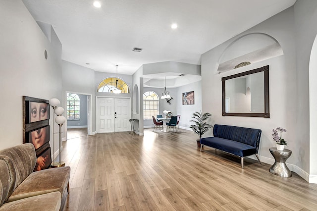 foyer entrance with a healthy amount of sunlight, light wood-type flooring, and a chandelier