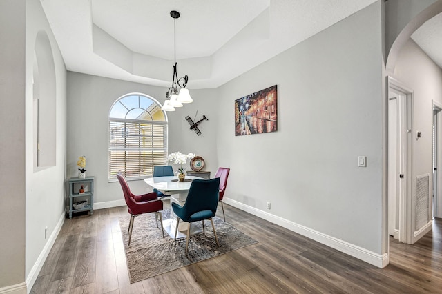 dining area featuring dark hardwood / wood-style floors and a raised ceiling