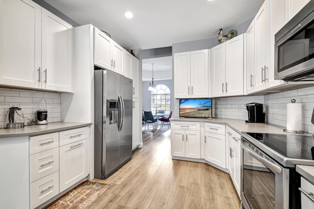 kitchen with white cabinets, decorative backsplash, light wood-type flooring, and stainless steel appliances