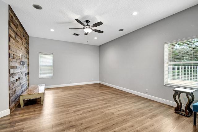 unfurnished room featuring plenty of natural light, light hardwood / wood-style floors, and a textured ceiling