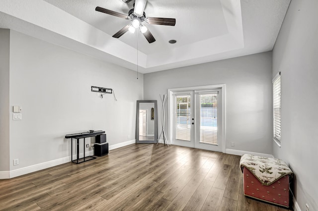 spare room featuring french doors, a textured ceiling, a raised ceiling, ceiling fan, and hardwood / wood-style floors