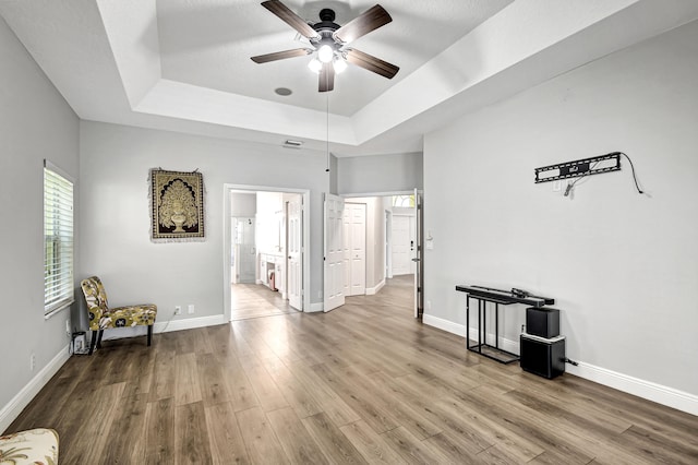 empty room featuring hardwood / wood-style flooring, a raised ceiling, and ceiling fan