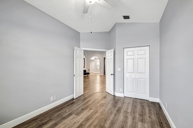 unfurnished bedroom featuring ceiling fan, high vaulted ceiling, hardwood / wood-style floors, a textured ceiling, and a closet