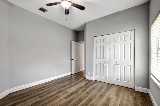 unfurnished bedroom with ceiling fan, a closet, a textured ceiling, and hardwood / wood-style flooring