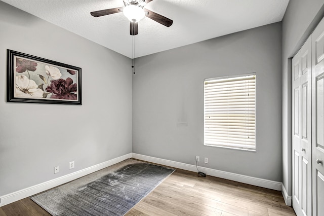 unfurnished bedroom with a textured ceiling, ceiling fan, light hardwood / wood-style flooring, and a closet