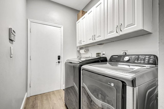 laundry area featuring cabinets, washer and dryer, and light wood-type flooring