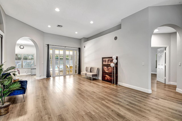 living area with a towering ceiling and light wood-type flooring