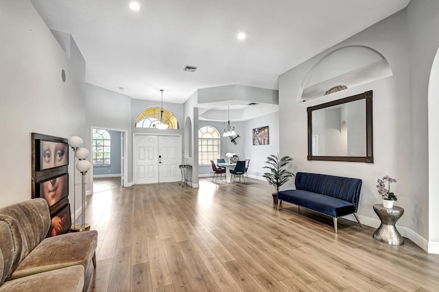 entrance foyer featuring a notable chandelier, plenty of natural light, and light wood-type flooring