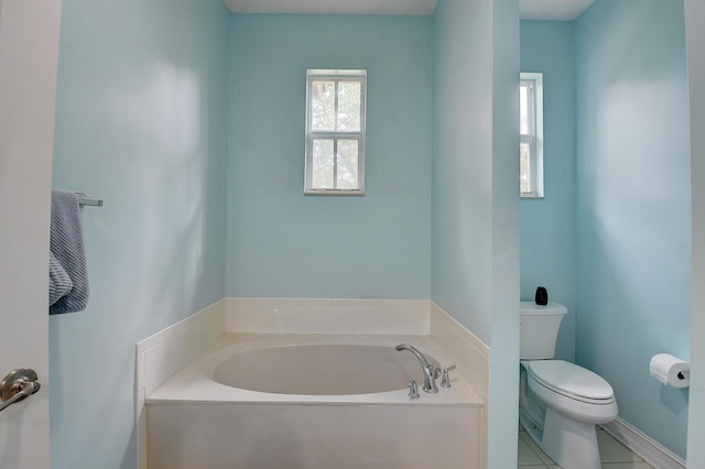 bathroom with tile patterned floors, toilet, and a tub to relax in