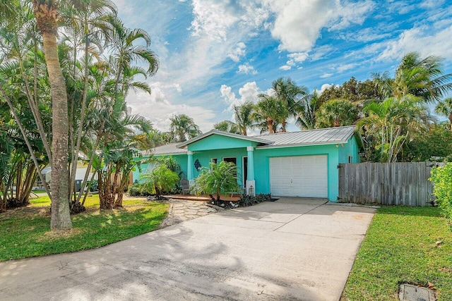 view of front of property featuring fence, stucco siding, concrete driveway, a front lawn, and a garage