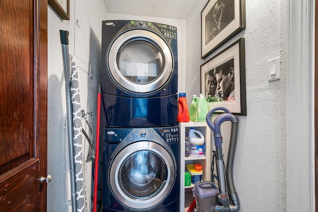 clothes washing area featuring laundry area, a textured wall, and stacked washer and dryer