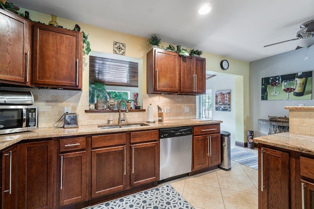 kitchen featuring light stone countertops, light tile patterned floors, stainless steel appliances, ceiling fan, and sink