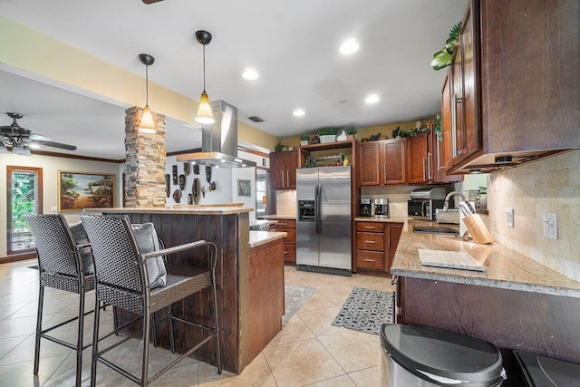 kitchen with pendant lighting, stainless steel refrigerator with ice dispenser, island exhaust hood, decorative backsplash, and ceiling fan