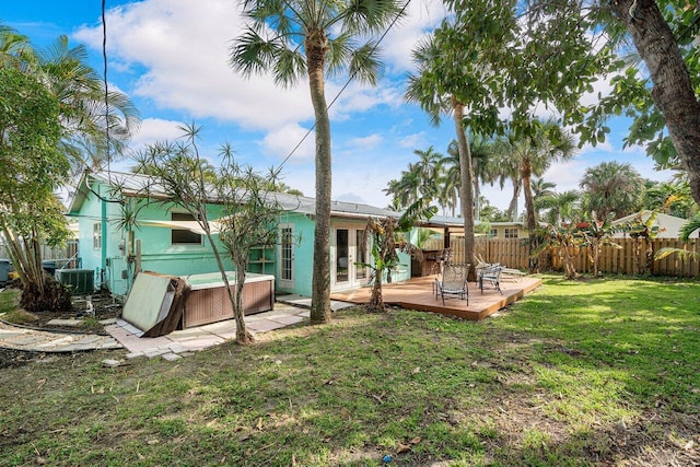 view of yard with central AC unit, fence, a hot tub, french doors, and a deck